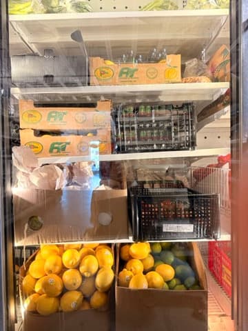 Fresh lemons, limes, and tomatoes in a store refrigerator