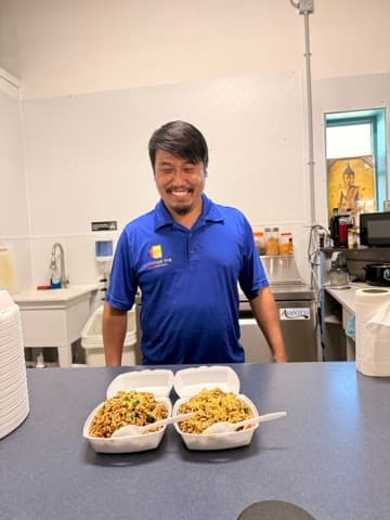 Shopkeeper smiling behind the counter with fresh food